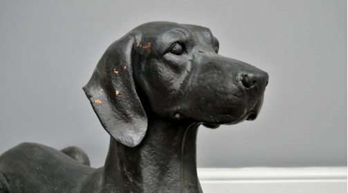 Estatua de perro sobre base de resina, 80cm de largo, acabado negro carbón efecto antiguo, ambiente de casa antigua