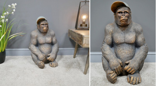 Representación de un gorila joven sentado, con gorra de lado, acabado marrón con reflejos dorados, 58cm.